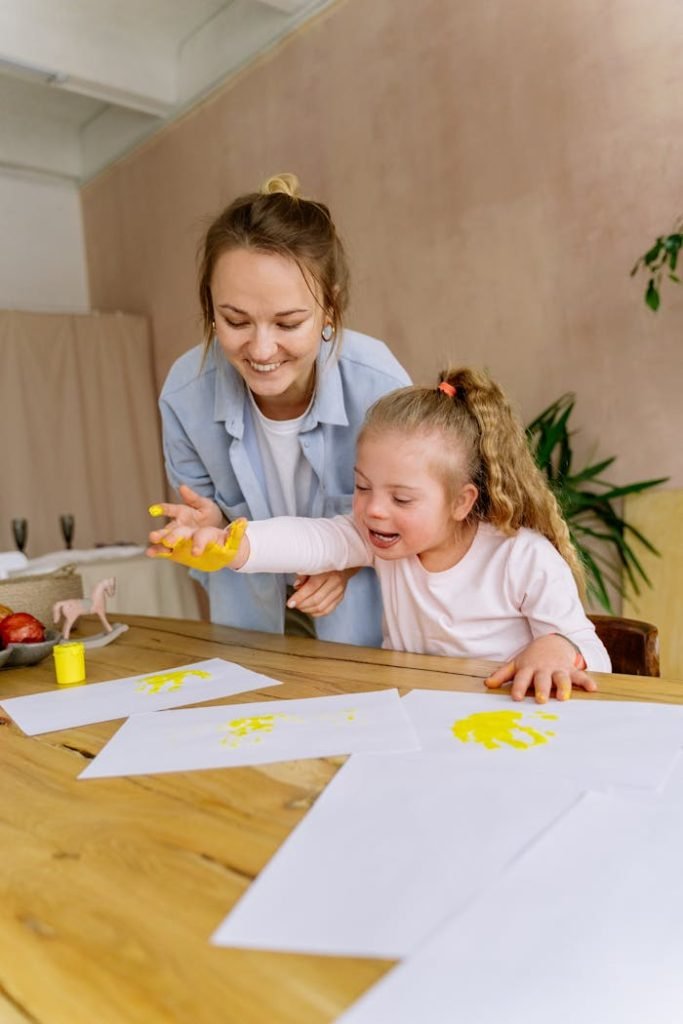 A mother and daughter enjoy a creative finger painting session together indoors.