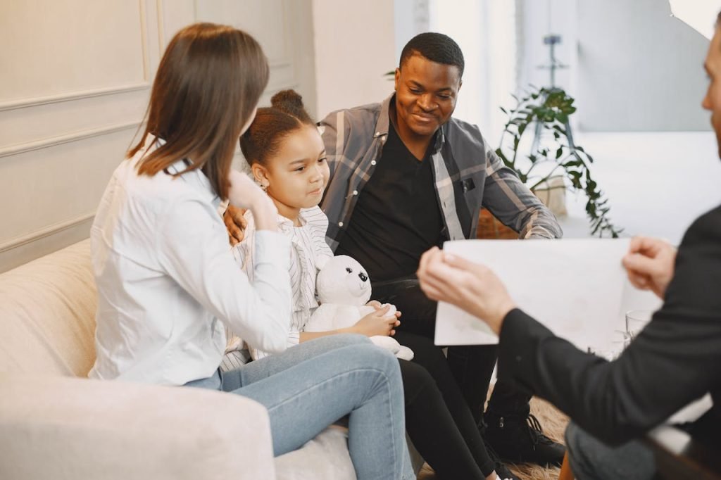 A family therapy session with a young girl, parents, and therapist discussing together.